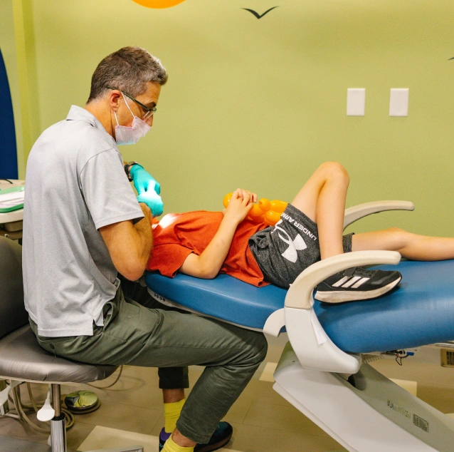 Pediatric dentist placing a tooth-colored composite filling for a young patient at Smile Zone in Springfield, MO.