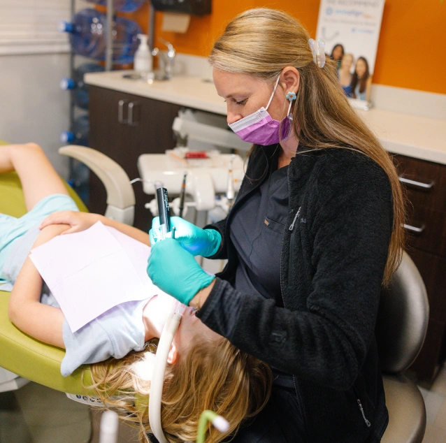 Dental professional applying fluoride varnish to a young patient's teeth at Smile Zone in Springfield, MO.