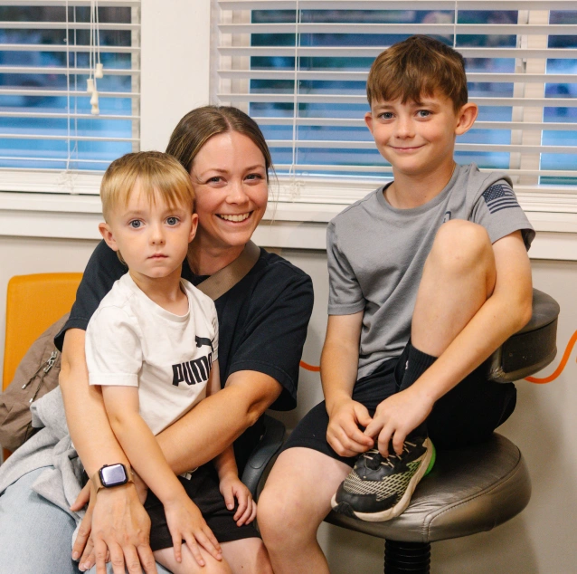 Parent and children smiling together during a pediatric dental visit at Smile Zone in Springfield, MO.