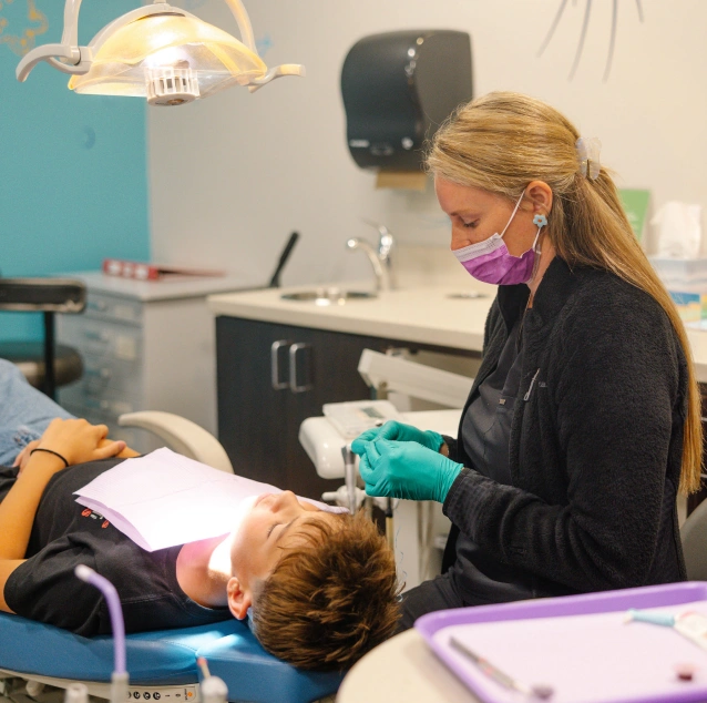 Pediatric dentist performing pulp therapy to save a child's infected baby tooth at Smile Zone in Springfield, MO.