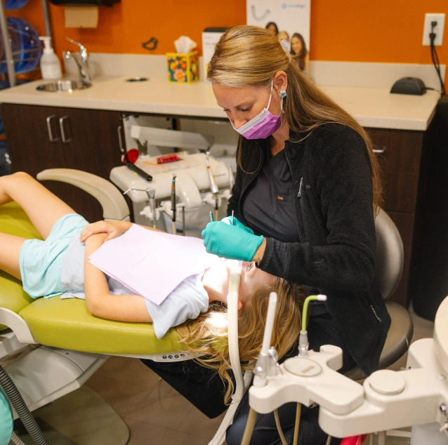 Pediatric dentist placing a stainless steel crown on a child's tooth at Smile Zone in Springfield, MO.